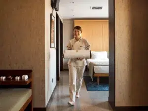 Divine Thai Spa A professional Thai massage therapist arriving at a hotel room with a rolled mat