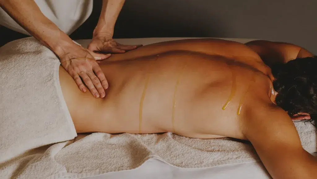 Oil Massage for Post-Gym Recovery in Bangkok A relaxing oil massage on an athletic person's back and shoulders after training