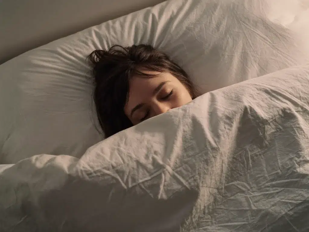 Outcall Massage and Sleep: How to Sleep Better in Bangkok A person sleeping peacefully and deeply under a soft duvet
