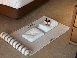 Divine Thai Spa A clean massage mat, folded towels and oil set out on a Bangkok hotel room floor, ready for a session